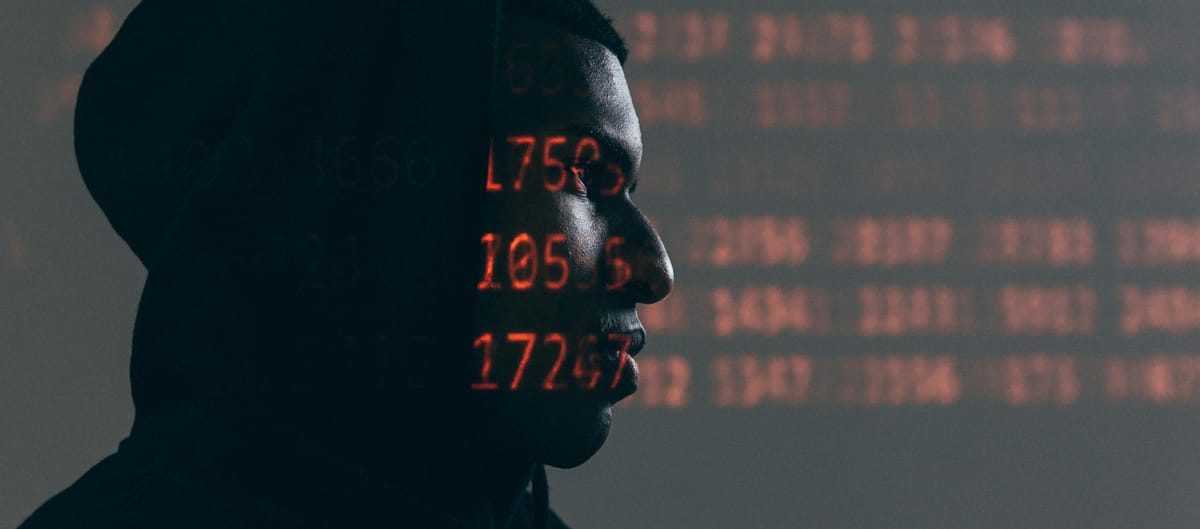 Person on a dark background with projected numbers over their face